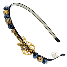 Load image into Gallery viewer, Decorative headband with gold guitar centerpiece and black and gold beads on a white background