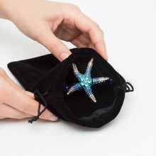 Load image into Gallery viewer, Starfish-shaped jewelry in a black drawstring bag held by hands on a white background
